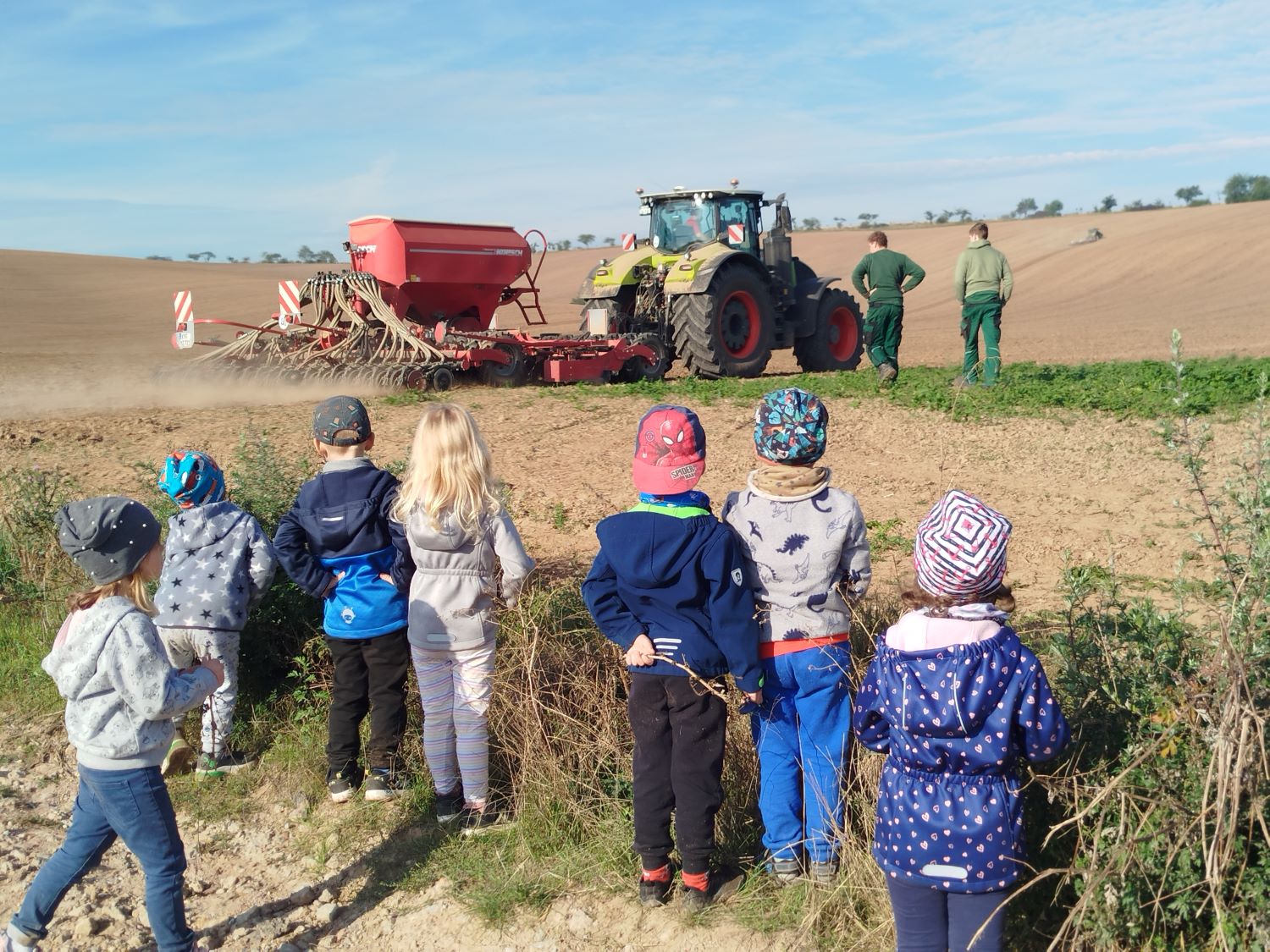 die Kinder schauen Bauern bei der Arbeit auf einem Feld zu